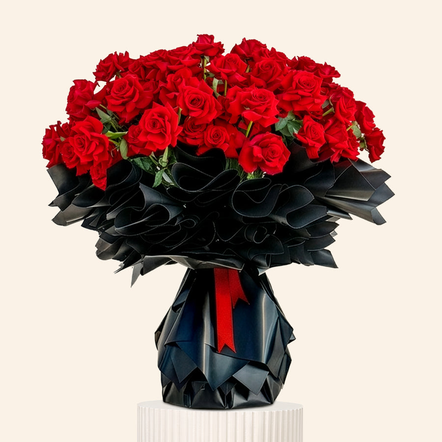 Bouquet of red roses in a black origami-style vase on a light gray background