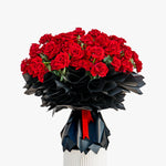 Bouquet of red roses in a black and white vase on a white background