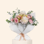 Bouquet of flowers wrapped in white paper on a light beige background