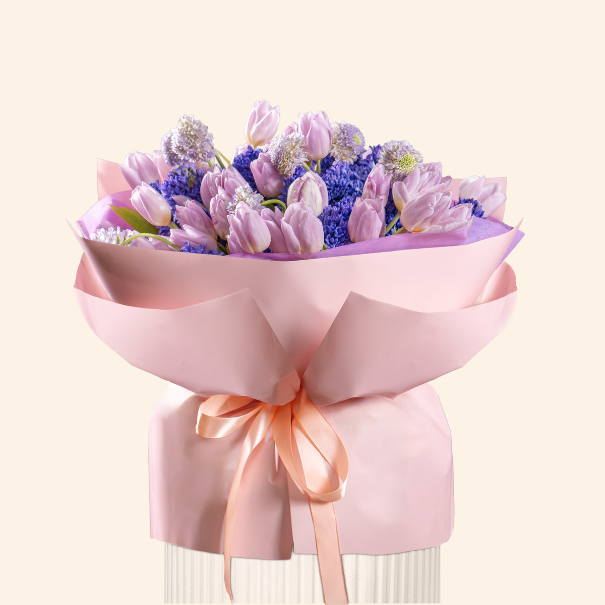 Bouquet of purple and pink flowers wrapped in pink paper with a ribbon on a white background