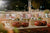 Outdoor evening event setup with wicker furniture, cushions, and decorative elements.