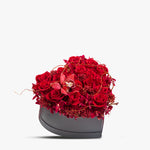 Bouquet of red flowers in a heart-shaped container on a white background