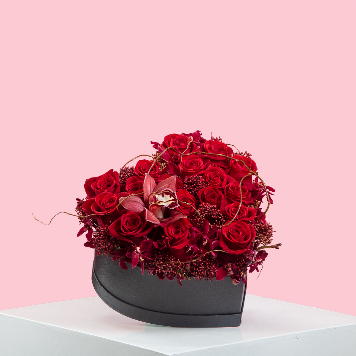 A heart-shaped box containing a vibrant red flower arrangement designed for Valentine's Day.