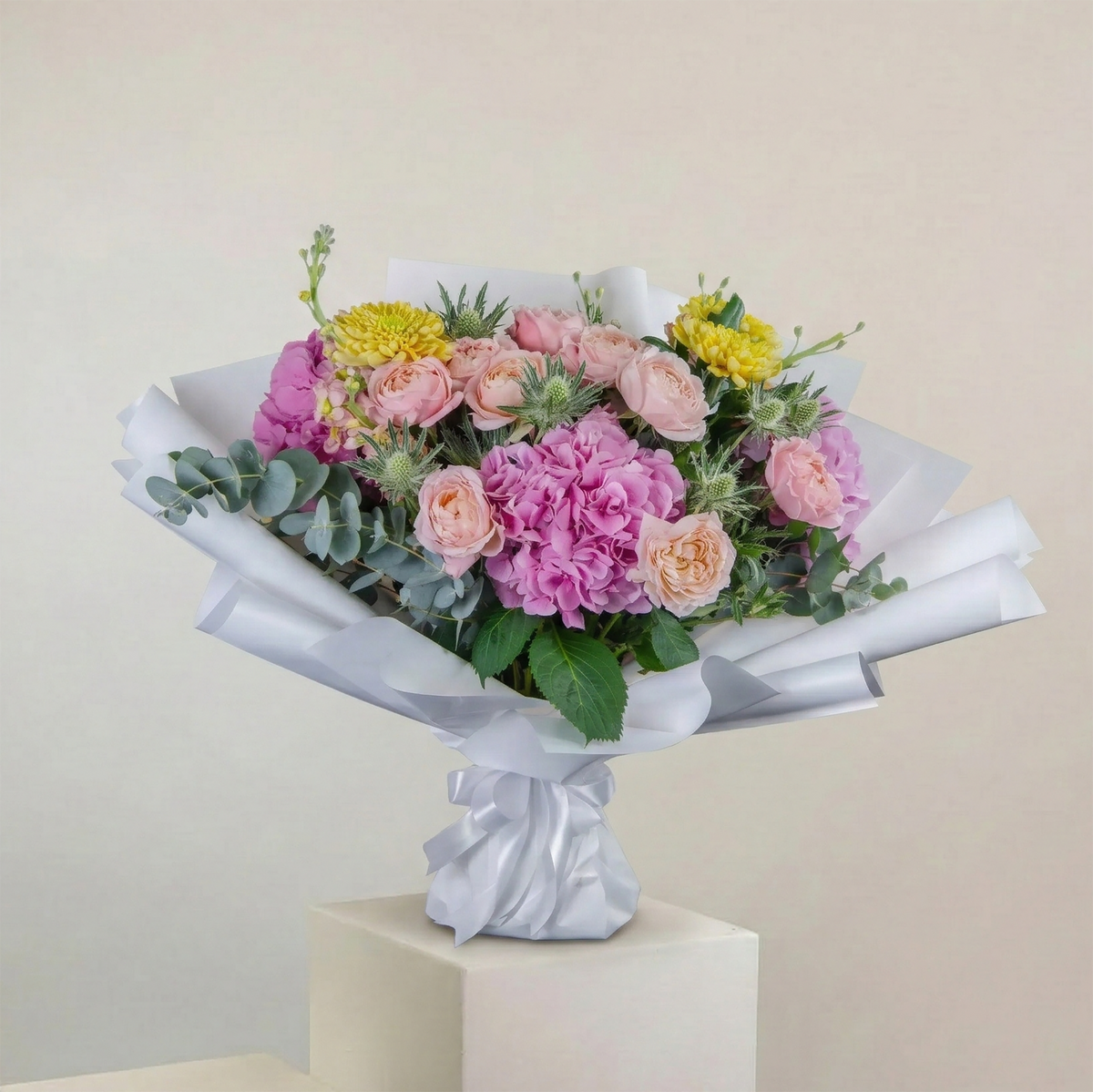 Bouquet of flowers wrapped in white paper on a beige background
