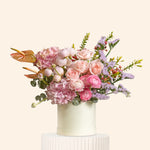 Floral arrangement with pink and white flowers in a white vase on a light background