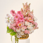 Bouquet of pink, white, and green flowers in a woven basket on a light background
