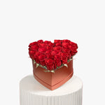 Heart-shaped box of red roses on a white pedestal with a white background