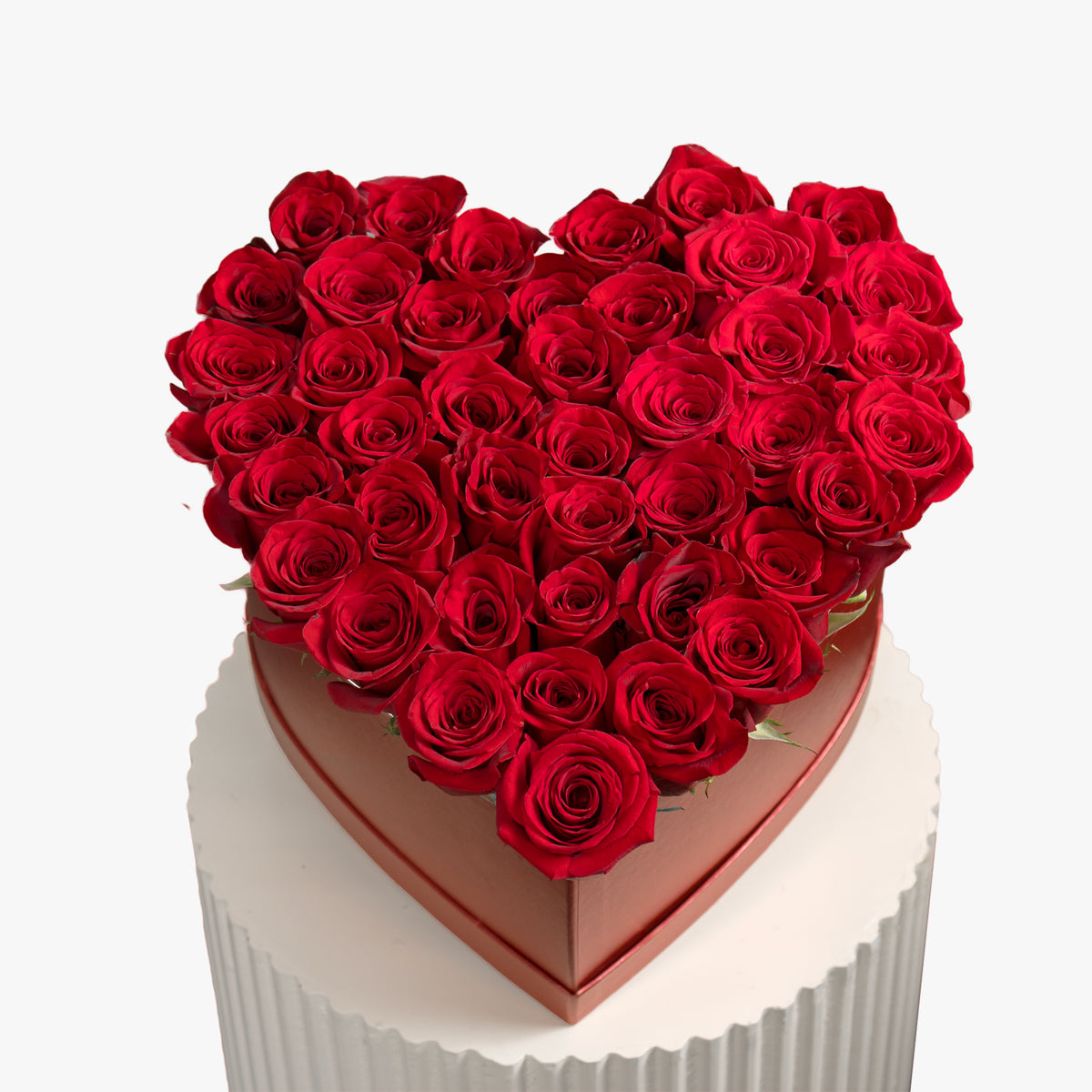 Heart-shaped box filled with red roses on a white background