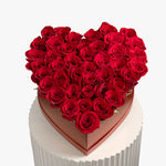 Heart-shaped box filled with red roses on a white background