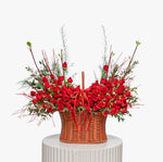 Basket of red roses with greenery on a white pedestal against a white background