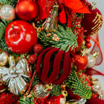 Close-up of a Christmas wreath with red and gold ornaments on a white background