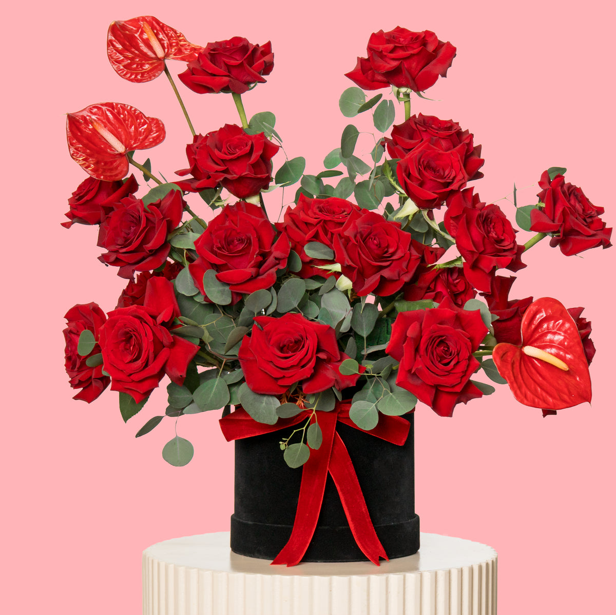Bouquet of red roses with greenery on a pink background