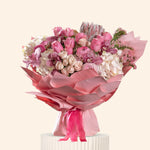 Bouquet of pink and white flowers with pink ribbons on a light background