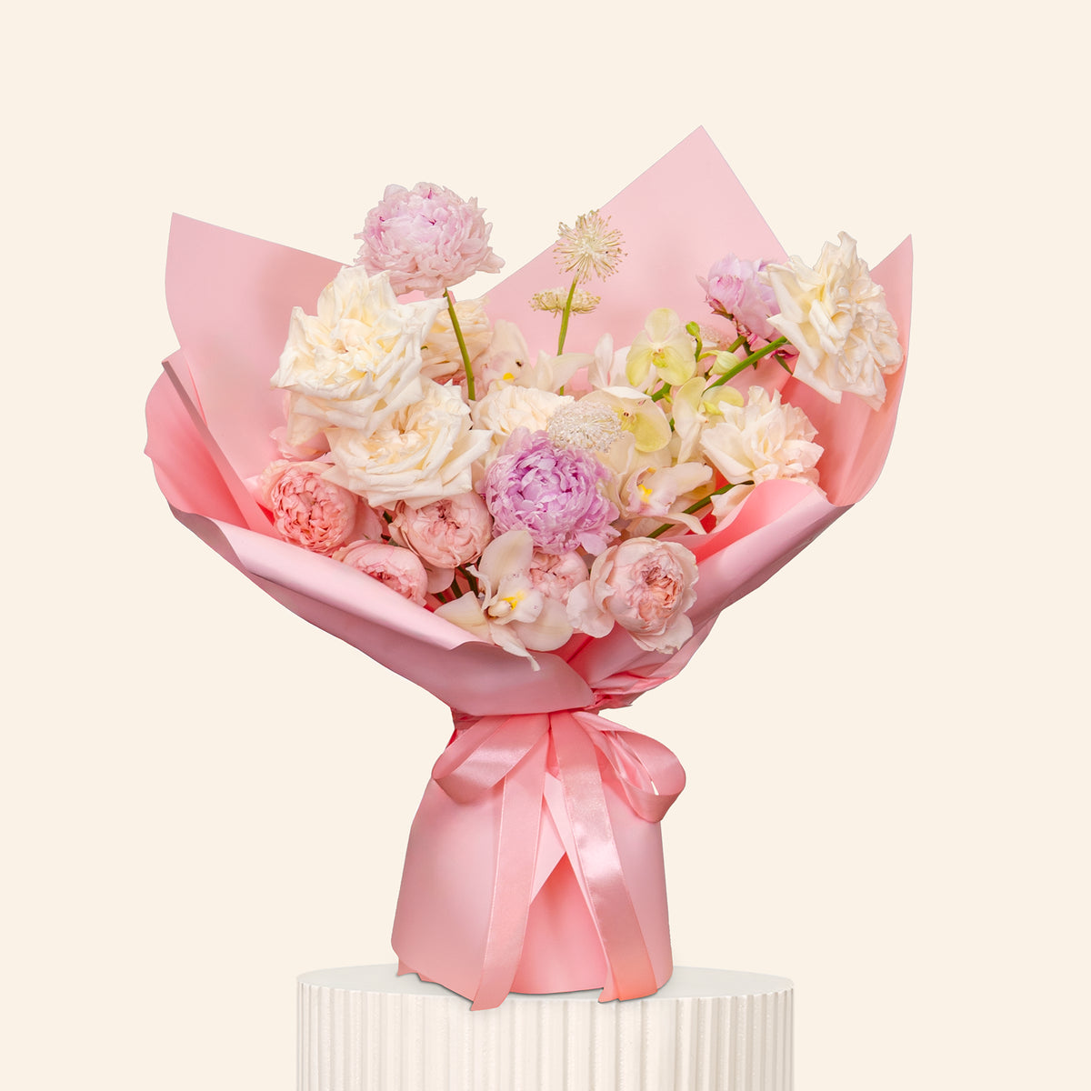 Bouquet of flowers wrapped in pink paper with a bow on a light beige background