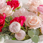 Bouquet of pink and red flowers with green leaves on a white background