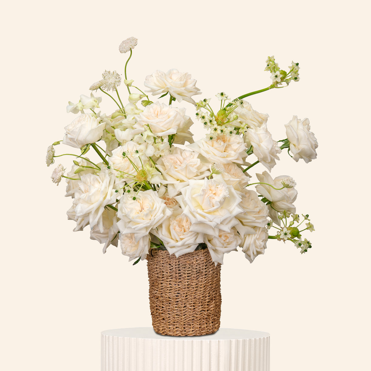 Bouquet of white flowers in a woven basket on a beige background