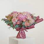 Bouquet of pink and white flowers wrapped in pink paper on a white background