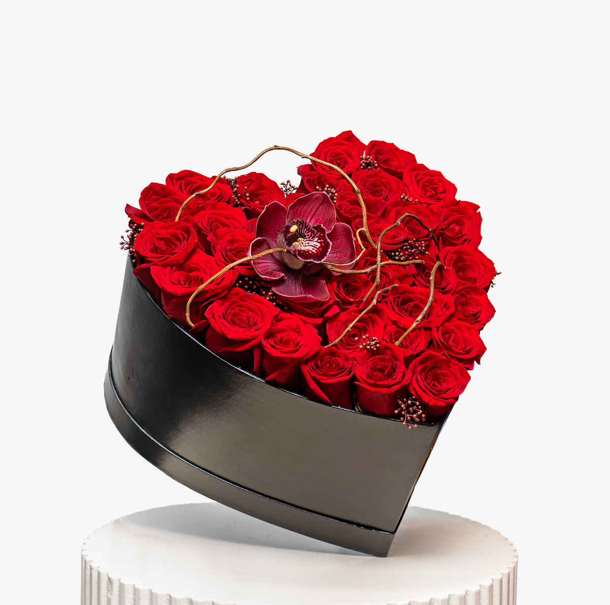 Heart-shaped box filled with red roses on a white background