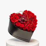 Heart-shaped box filled with red roses on a white background