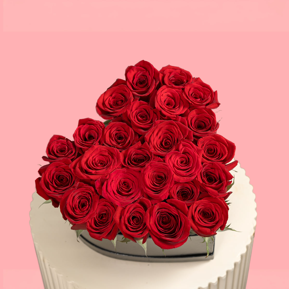 Heart-shaped arrangement of red roses on a pink background