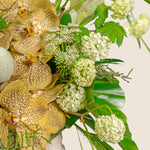 Bouquet of yellow orchids and white flowers with green leaves on a light background