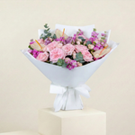 Bouquet of pink roses and hydrangeas with a white wrap on a beige background